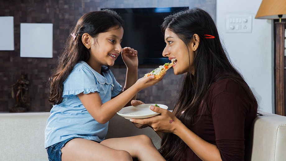 Daughter offing a pizza slice to her mother
